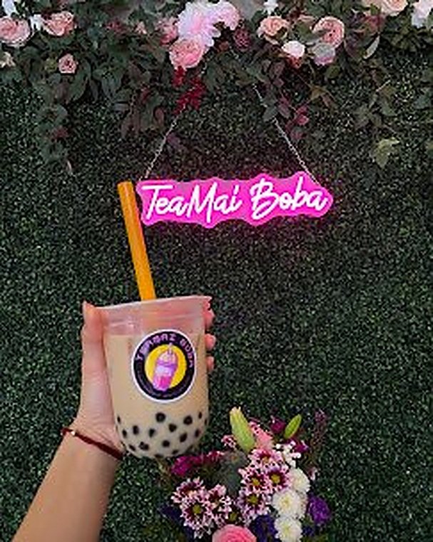 TeaMai Boba pink neon sign on flower wall